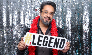 George Velasco holding a photo booth sign #legend and smiling.